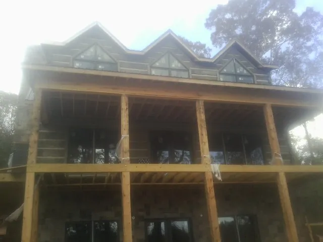 Dormers and porch framing on a large log home under construction — Roof Coating work by our crew in Huntingdon