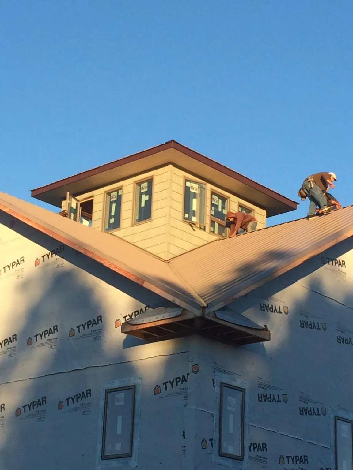 Roofers working around a rooftop cupola on a new metal roof at sunset — Roof Waterproofing in Huntingdon by Roofing Brothers